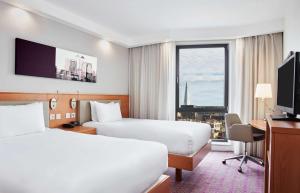 a hotel room with two beds and a desk and a window at Hampton by Hilton London Waterloo in London