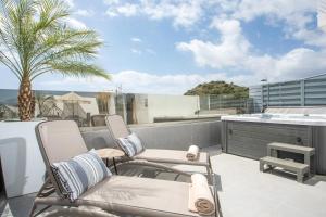 a balcony with two chairs and a kitchen and a palm tree at JnS Premium Stay in Faliraki