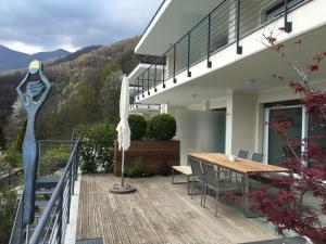 una casa con terrazza in legno con tavolo e ombrellone di Casa La Solaria a Cannero Riviera