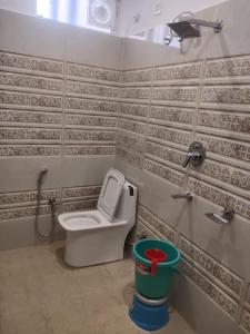 a bathroom with a toilet and a green bucket at Hotel prisha pahal Home stay in Uttarkāshi