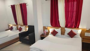 a room with two beds and a chair and red curtains at Hotel prisha pahal Home stay in Uttarkāshi