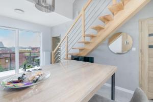 a living room with a wooden table and stairs at Apartament Holiday Pelican in Rewal