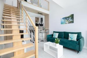 a living room with a green couch and stairs at Apartament Holiday Pelican in Rewal
