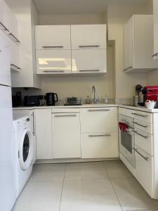 a kitchen with white cabinets and a washer and dryer at Cap d ail 2 pièces proches Monaco et plage in Saint-Antoine +3 photos