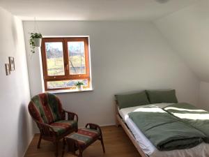 a bedroom with a bed and a chair and a window at Ferienwohnung Weitblick - Urlaub in der Natur und trotzdem nah an Ausflugszielen in Mainleus