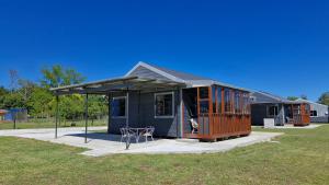 a tiny house with a porch and two chairs at Hen & Hound in Gqeberha +11 photos