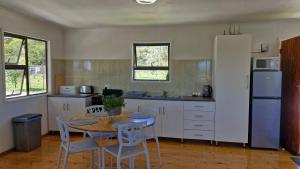 a kitchen with a table and chairs and a refrigerator at Hen & Hound in Gqeberha