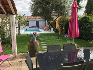 a patio with a table and a pink umbrella at Maison typique Bordeaux avec piscine in Bègles