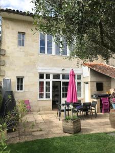a house with a pink umbrella in the yard at Maison typique Bordeaux avec piscine in Bègles