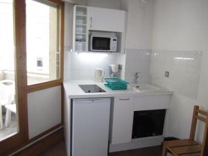 eine weiße Küche mit Spüle und Mikrowelle in der Unterkunft Studio Centre Brides-les-Bains avec WIFI et Parking - FR-1-512-132 in Brides-les-Bains