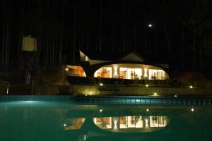 a building at night with a reflection in a swimming pool at Ginberry Holidays in Wayanad