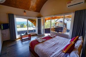 a bedroom with a large bed with large windows at Ginberry Holidays in Wayanad