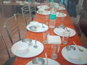 a long table with white plates and bowls on it at Green Mountain View Himachal Pradesh With Restaurant in Shimla