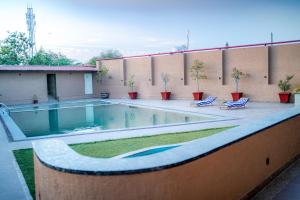 a swimming pool on a patio with two lounge chairs at Imperia Resort by The Sky Imperial, Nathdwara in Nāthdwāra