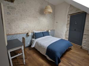 a bedroom with a bed with blue pillows and a table at La Sourcière Beaugency in Beaugency