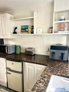 a kitchen with white cabinets and a counter top at Priory Barn Apartment in Street