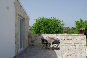 a patio with a table and chairs on a stone wall at Villa Andrè with private pool in Val di Noto in Noto +32 photos