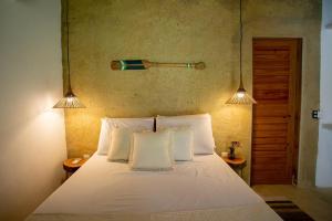 una camera da letto con un letto bianco con due luci sopra di Casa Elbacha a Trancoso