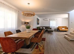 a dining room and living room with a table and chairs at Villa Kortus Luxury modern villa near Petram Resort, beach 700m and Adriatic golf resort in Savudrija