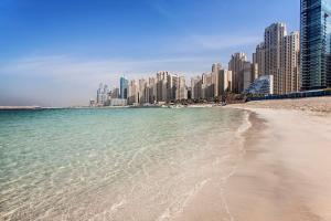 a beach in front of a city with tall buildings at Hilton Dubai The Walk in Dubai