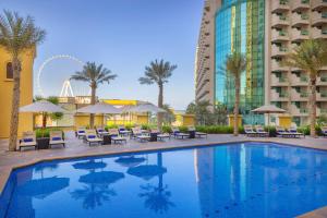 a swimming pool with chairs and a hotel at Hilton Dubai The Walk in Dubai