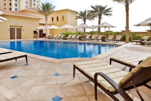 a swimming pool with chairs and umbrellas at a hotel at Hilton Dubai The Walk in Dubai