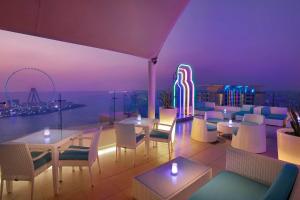 a restaurant with tables and chairs and a roller coaster at Hilton Dubai The Walk in Dubai