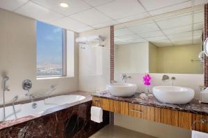 two sinks in a bathroom with a large mirror at Hilton Dubai The Walk in Dubai