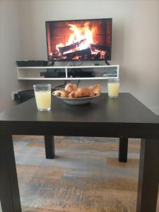 a table with a bowl of bread and two glasses of orange juice at S Bourgeois 2 Charmant T3 tout équipé au centre in Sedan +18 photos