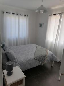 a bedroom with a bed and white curtains at Little Seacastle in Pearly Beach
