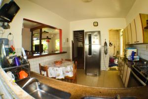 a kitchen with a table and a stainless steel refrigerator at Solange apartment-Casa em Ilheus-Olivença in Olivença
