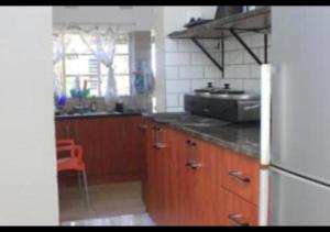 a kitchen with wooden cabinets and a white refrigerator at Bennyz Guest House in Pretoria