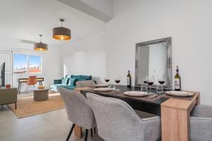 Modern seaview apartment in the heart of Agia Napa في أيا نابا: غرفة معيشة مع طاولة طعام مع كؤوس للنبيذ