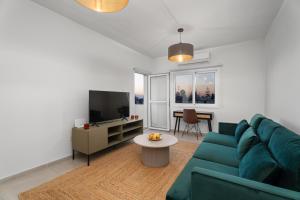 Modern seaview apartment in the heart of Agia Napa في أيا نابا: غرفة معيشة مع أريكة خضراء وتلفزيون