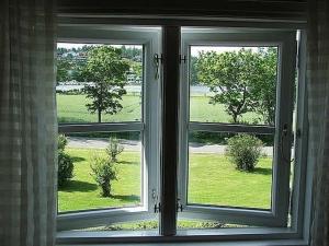 an open window with a view of a green field at Cozy house with sea view at Husvik, 3 bedrooms in Tønsberg