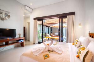 dos cisnes están sentados en una cama en un dormitorio en Villa O'Anne II, en Seminyak