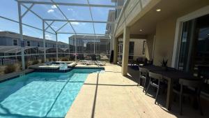 a swimming pool with chairs and a table on a building at Upstay ChampionsGate Home w Pool BBQ & Game Room in Kissimmee
