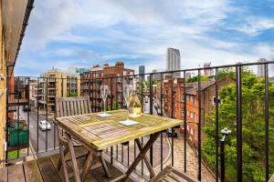 einen Balkon mit einem Holztisch und Stadtblick in der Unterkunft Cozy 2 Bedroom Waterloo London Bridge in London