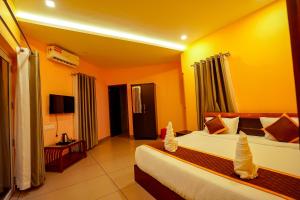 a hotel room with two beds and a television at Ginberry Holidays in Wayanad