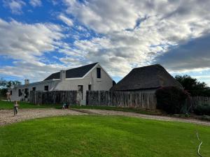 a large white barn with a fence in front of it at Little Nyati farmstay in Somerset East