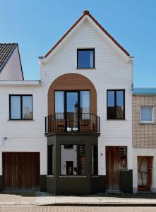 ein weißes Haus mit einem Balkon auf der Vorderseite in der Unterkunft SUNSET, Maison Littoral by BLOSS, stylish family apartment near the beach with terrace in De Haan