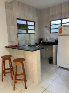 a kitchen with two stools and a counter and a refrigerator at Natureza Viva in Camacari +7 photos