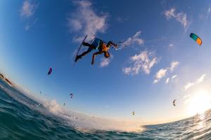 a man flying in the air over the ocean at Deich&Düne Nordsee -Apartment in Schillig