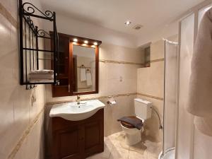 a bathroom with a sink and a toilet and a mirror at VISTA MARE Kythera House in Agia Pelagia