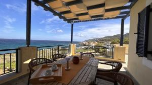 a wooden table on a balcony with a view of the ocean at VISTA MARE Kythera House in Agia Pelagia