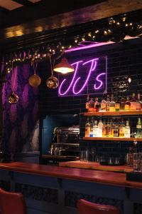 a bar with a neon sign on the wall at The Old Crown Coaching Inn in Faringdon