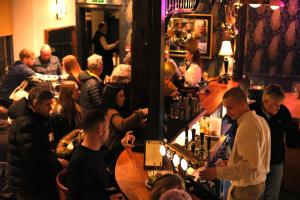 a crowd of people standing around a bar in a pub at The Old Crown Coaching Inn in Faringdon +89 photos