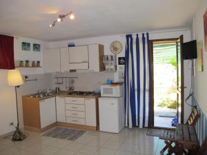 une cuisine avec des placards blancs et une porte donnant sur une terrasse. dans l'établissement Monolocale Via Panoramica, à Rio Marina