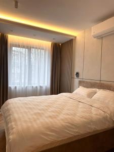 a bedroom with a large white bed with a window at CHANTTAL Luxury - AMZEI in Bucharest