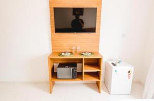 a table with a microwave and a tv on a wall at William santos Garcia in Natal